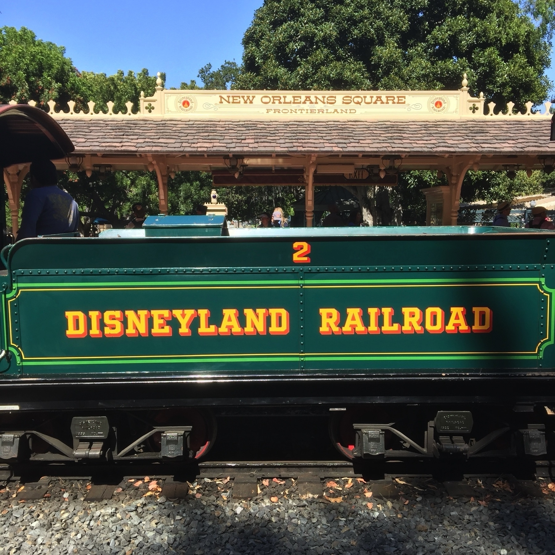 A dark green train Disneyland Railroad train car passing through New Orleans Square in Frontierland.