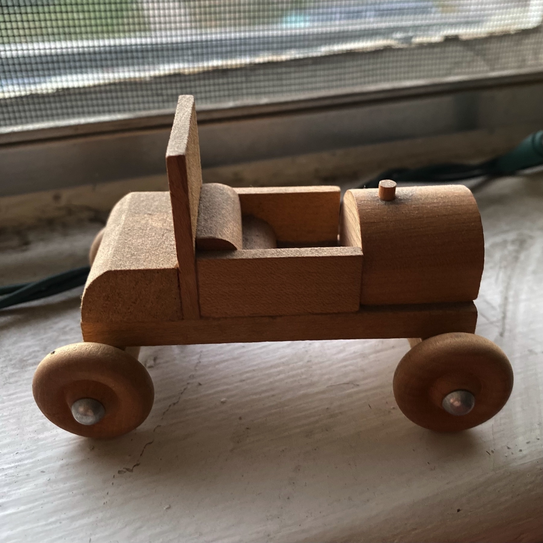 A small wood toy car, assembled from a kit and glued together.